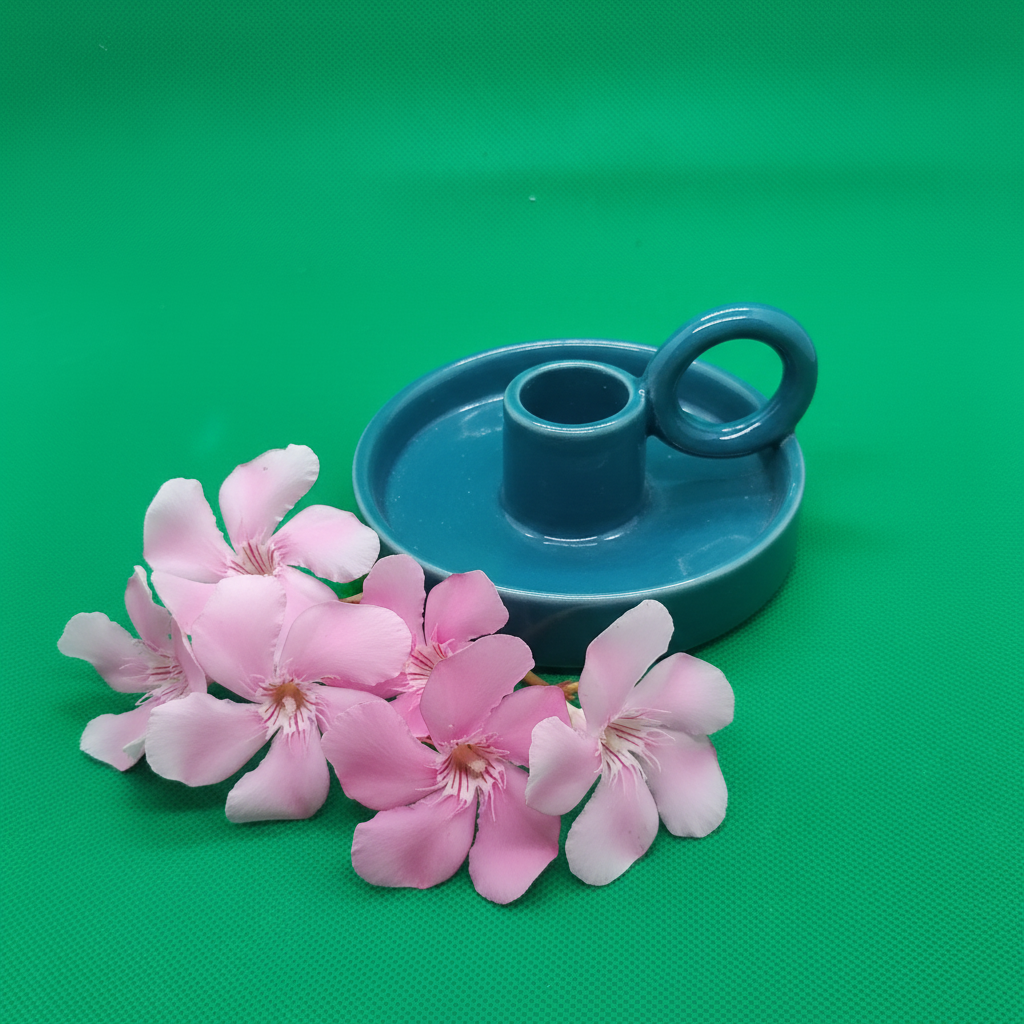 Bougeoir céramique bleu avec anse sur fond vert avec fleurs roses